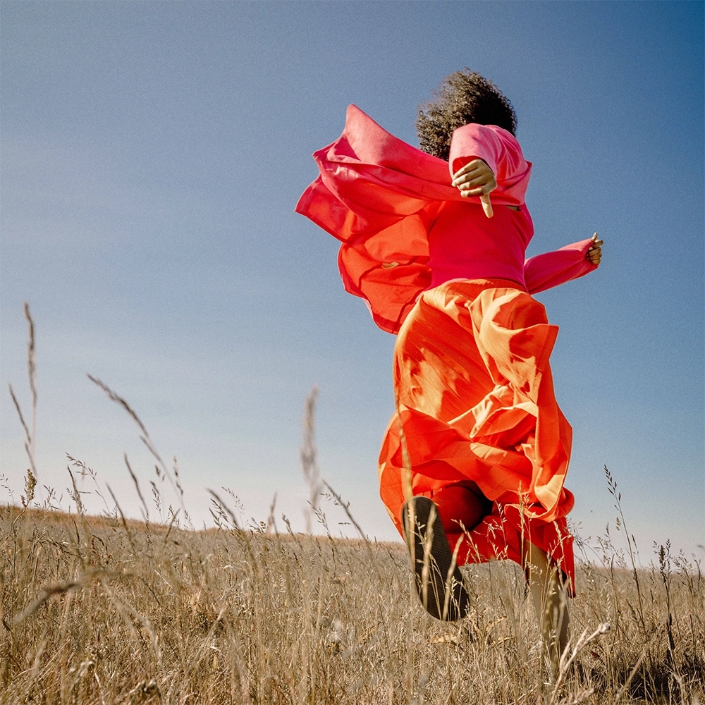 Woman in a orange dress running across a field