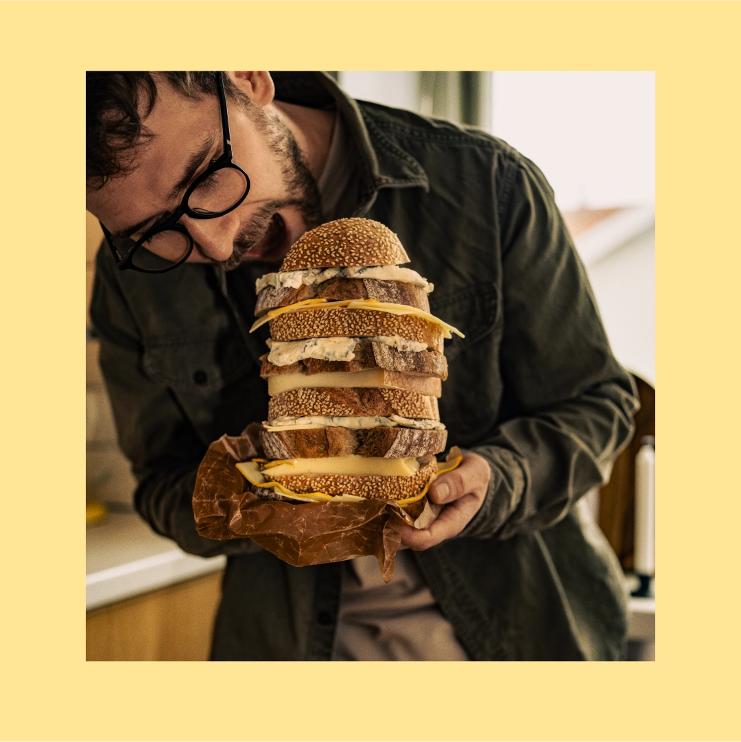 Man holding a high sandwich wich cheese - Ny Studio