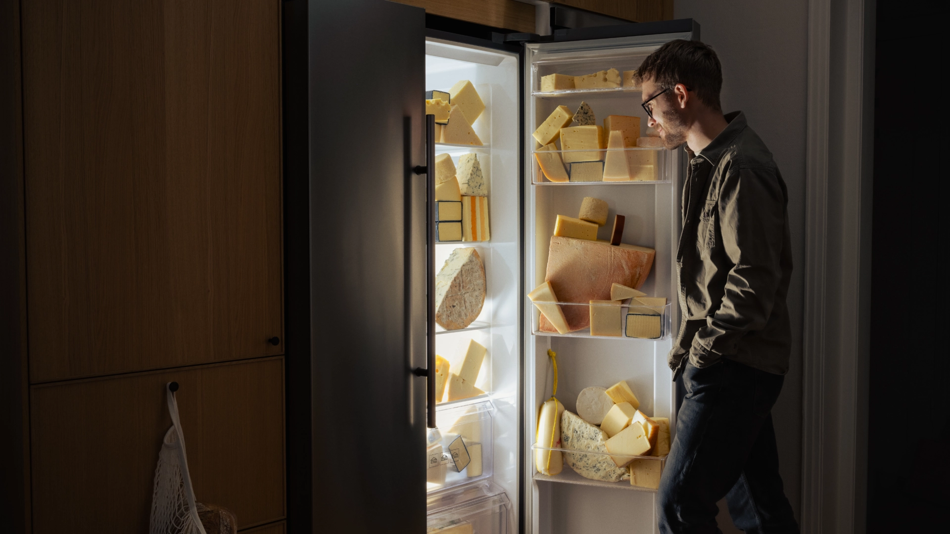 Man opening a fridge filled with cheese - Ny Studio