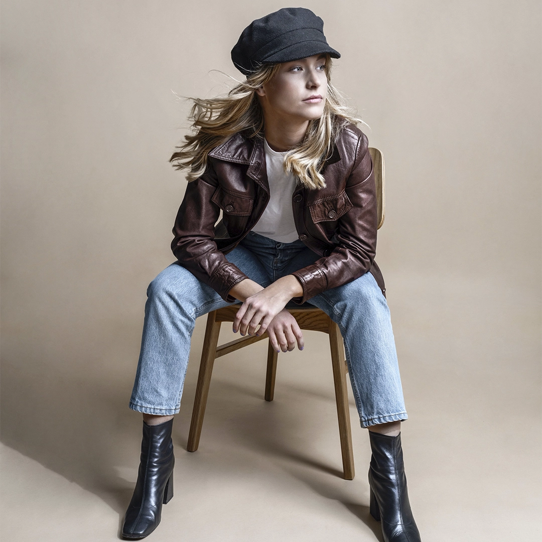 Woman sitting "manly" on a chair, arms resting on her knees