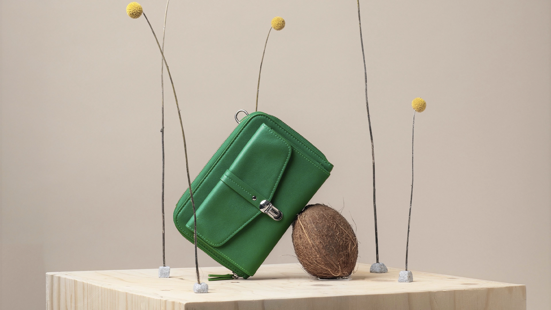 Brand imagery for PMU a green purse resting on top of a coconut. 5 Yellow flowers loosely spread in the background - NyStudio