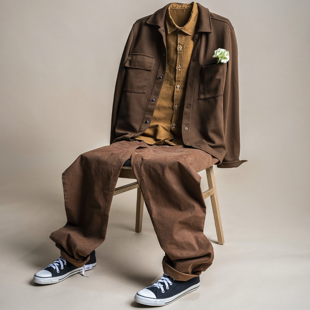 Clothes on a chair formed as a human sitting on the chair. Brand imagery for PMU second hand by NyStudio